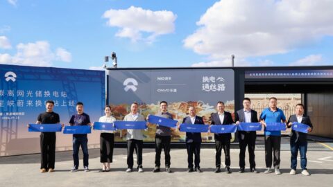 Guests hold blue Nio banners at the opening ceremony for the Xingxingxia solar-powered battery swap station.
