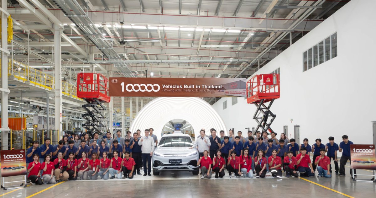 BYD's Thailand team poses around a white Atto 3 at the Rayong plant beneath a banner celebrating 100,000 vehicles built in Thailand.