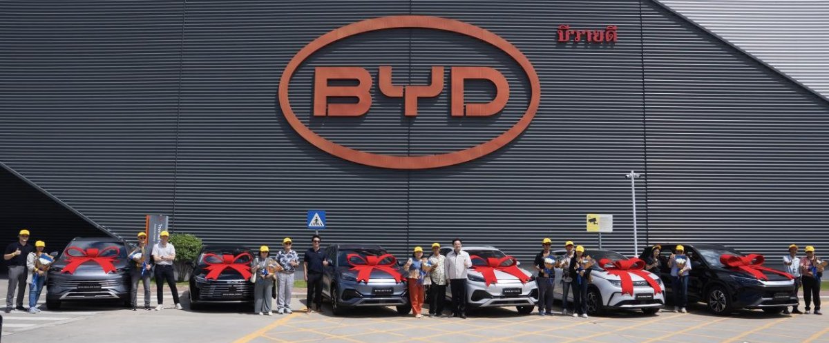 Participants pose beside BYD vehicles decorated with red bows during a handover ceremony outside the company's Thailand plant.