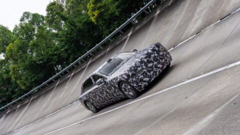Camouflaged Yangwang executive sedan prototype driving along a steeply banked test track.