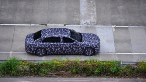 Overhead view of a camouflaged Yangwang executive sedan prototype on a concrete test track.