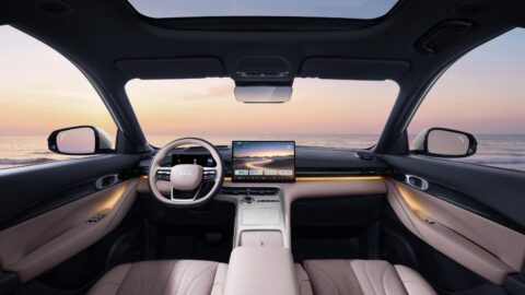 Geely Galaxy E5 cabin viewed from the rear seats, showing the steering wheel, central touchscreen and panoramic glass roof.