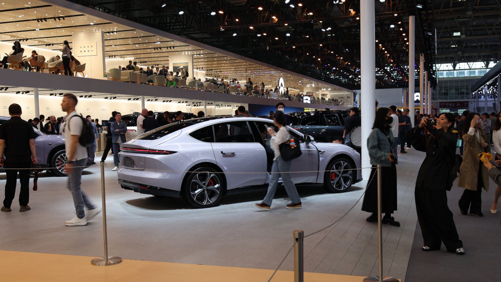 Visitors walk past a light purple Nio sedan at the automaker's booth at the Beijing Auto Show in April 2026.