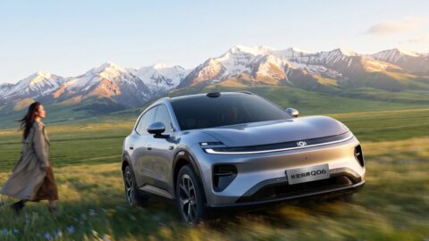 Silver Changan Nevo Q06 SUV in a grassy meadow with snow-capped mountains in the background.