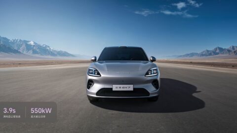 Front view of a silver Aistaland GX7 SUV on an open road, with snow-capped mountains in the distance.