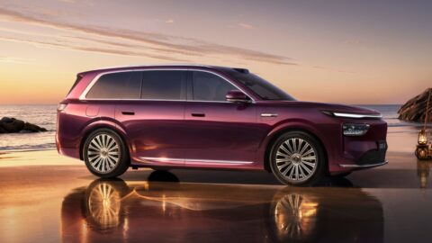 Side profile of a burgundy Epicland X9 SUV parked beside the water at sunset.