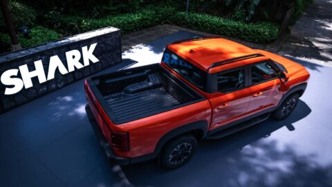 Elevated rear three-quarter view of an orange BYD Shark pickup showing its open cargo bed.