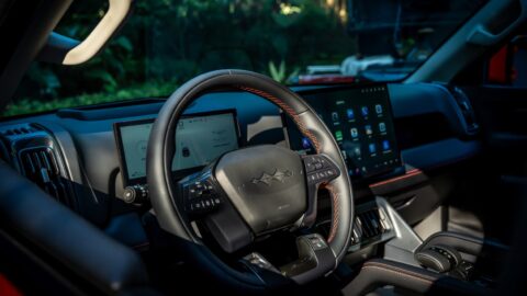 Angled view of the BYD Shark cockpit showing the steering wheel, digital displays and orange interior stitching.