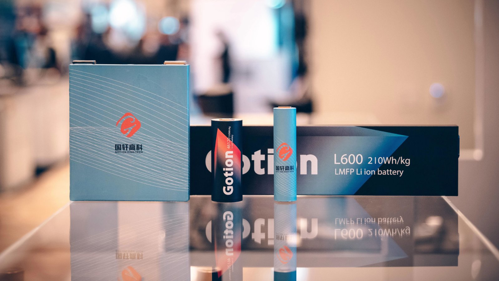 Gotion High-tech prismatic and cylindrical battery cells on display alongside an L600 LMFP battery labeled with an energy density of 210 Wh/kg.