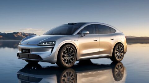 Silver Luxeed R7 shown from a front three-quarter angle on a reflective surface with mountains in the background.