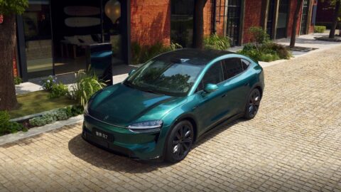 Green Luxeed R7 viewed from above on a cobblestone street beside brick buildings.