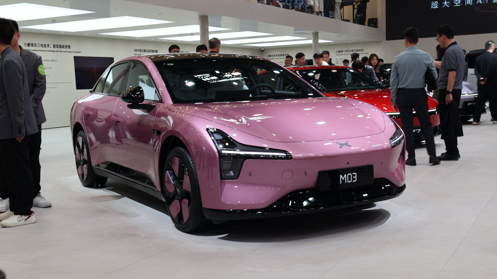 Pink Xpeng Mona M03 electric sedan on display at the Beijing Auto Show in April 2026, viewed from the front three-quarter angle.