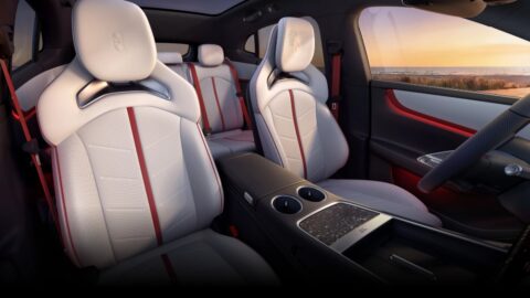 Luxeed RX cabin with sculpted white seats, red seat belts and a center console with cupholders.