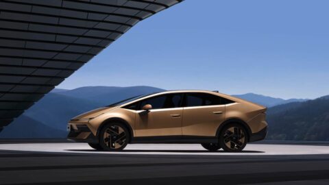 Side profile of a gold Hyundai Ioniq V, showing its sloping roofline beneath a curved canopy.