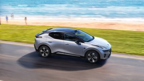 Silver Lynk & Co 20 electric SUV driving along a coastal road beside a sandy beach.