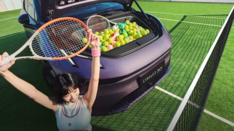Open front trunk of a purple Lynk & Co 20 filled with tennis balls and rackets on a tennis court.