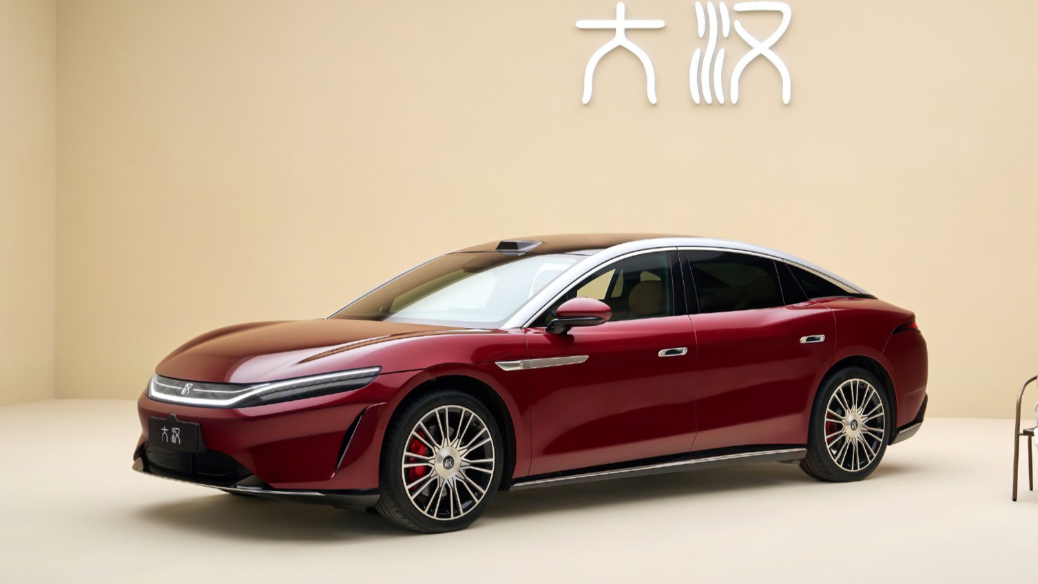 Red BYD Da Han flagship sedan with a silver roof, shown from a front three-quarter angle indoors.