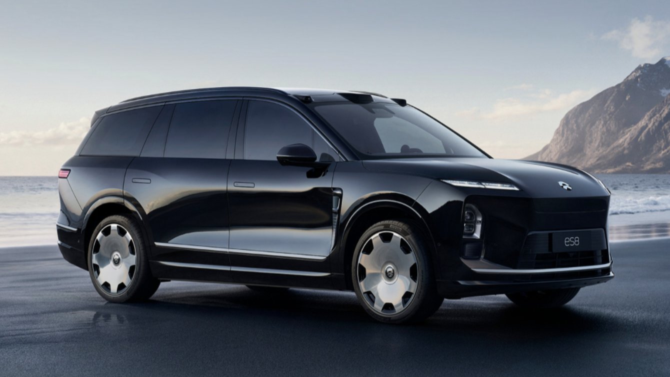 Black third-generation Nio ES8 SUV shown from a front three-quarter angle beside the sea, with mountains in the background.