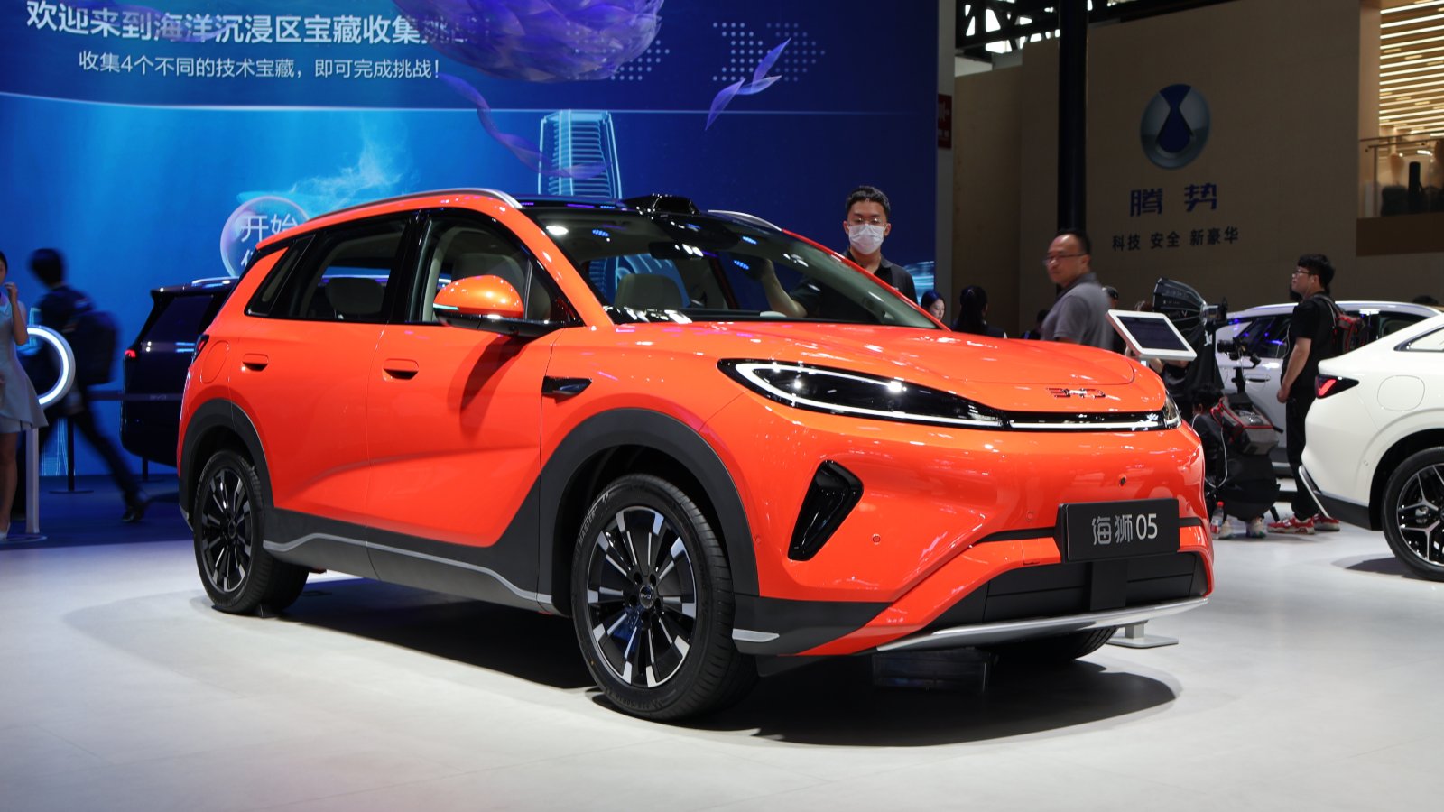 Front three-quarter view of an orange BYD Sealion 05 SUV with a black roof at the Beijing auto show in April 2026.