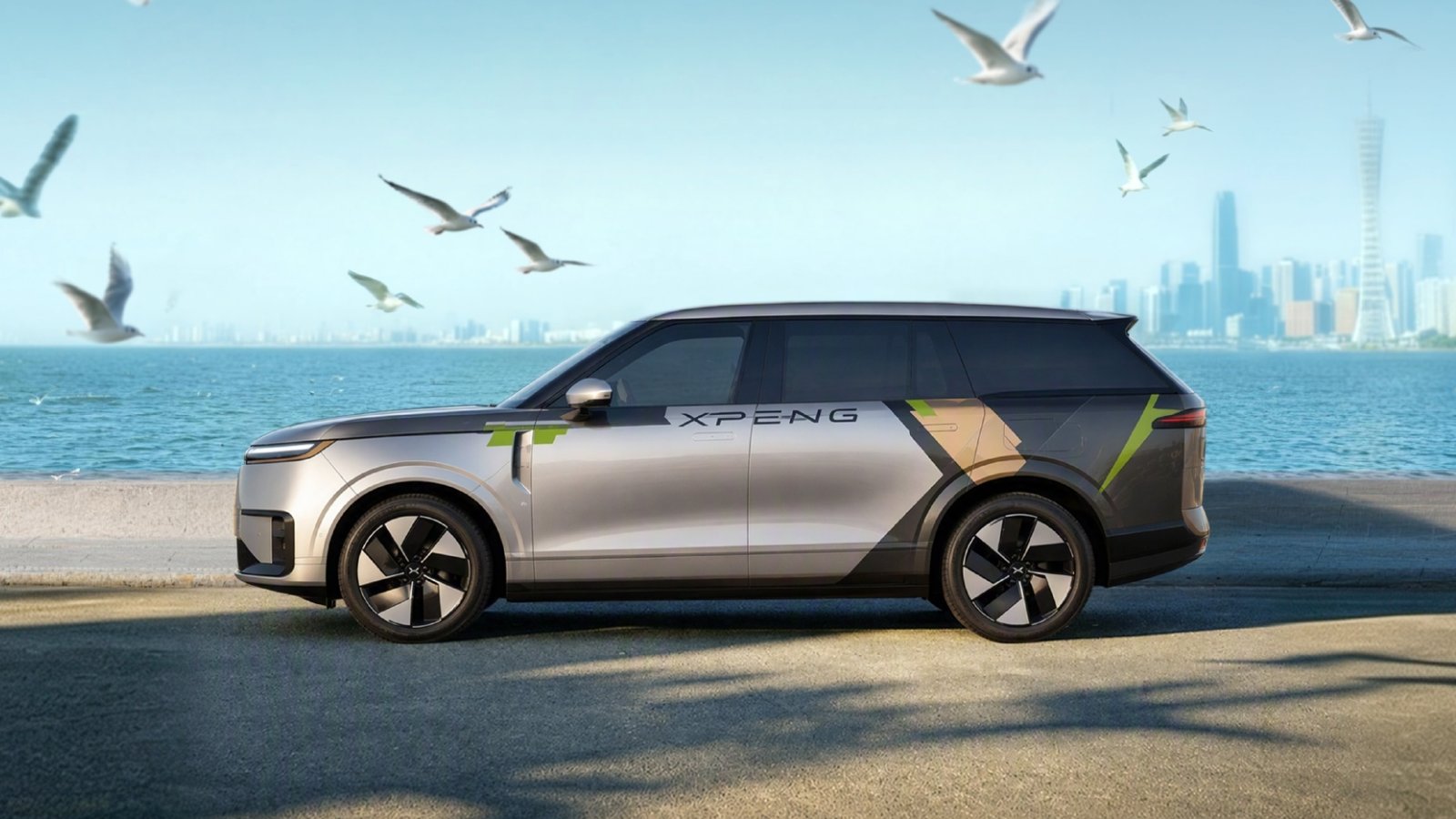 Side view of the Xpeng Yoyo robotaxi with silver and dark gray bodywork beside a waterfront in a promotional image.