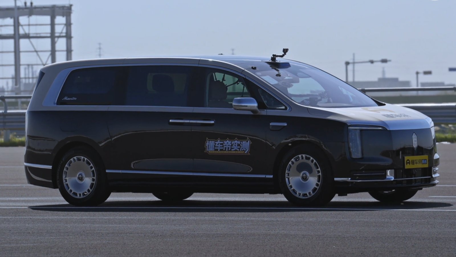 Side view of a dark gray Maextro V800 MPV fitted with roof-mounted cameras on a test track.