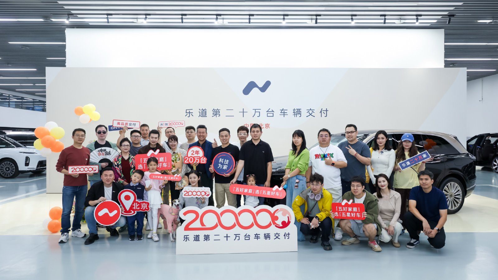Attendees pose beside an Onvo L90 with signs celebrating the brand's 200,000th vehicle delivery in Beijing.