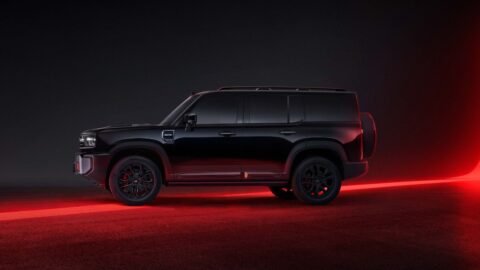 Side profile of a dark Geely Galaxy Cruiser 700 under red studio lighting.