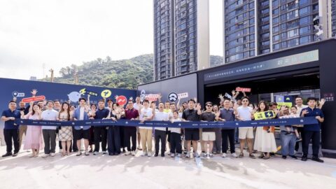 A large group poses with signs and a long blue banner outside a Nio battery swap station.