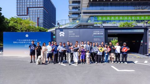 Attendees pose outside a Nio battery swap station beside a blue backdrop marking 500 stations in Guangdong.