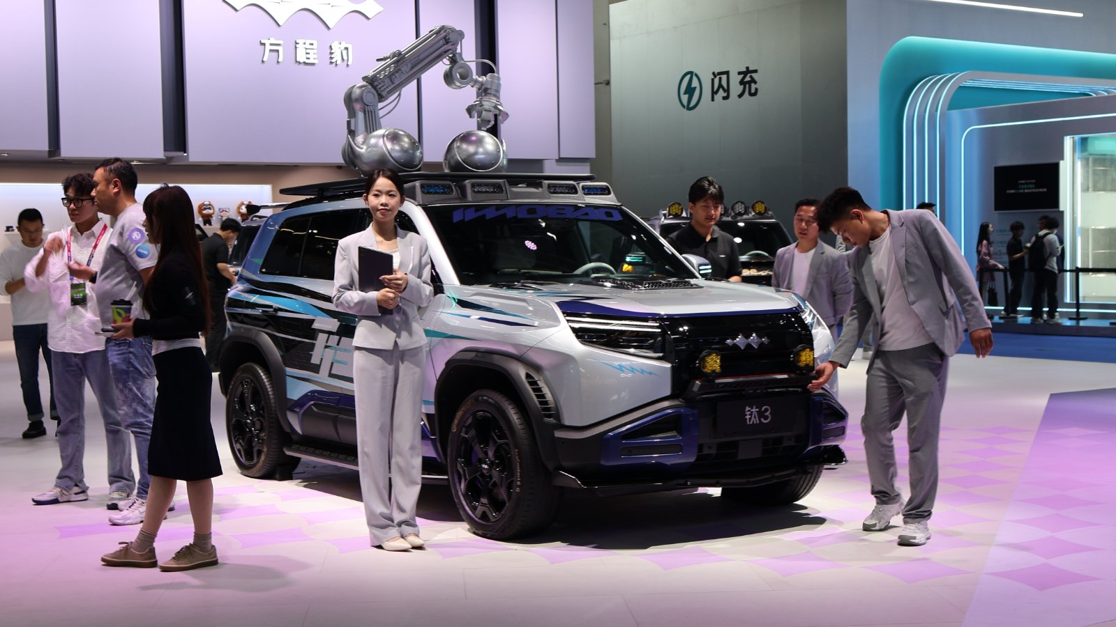 BYD Fang Cheng Bao Tai 3 SUV with a silver body and colorful graphics, surrounded by visitors at an auto show.