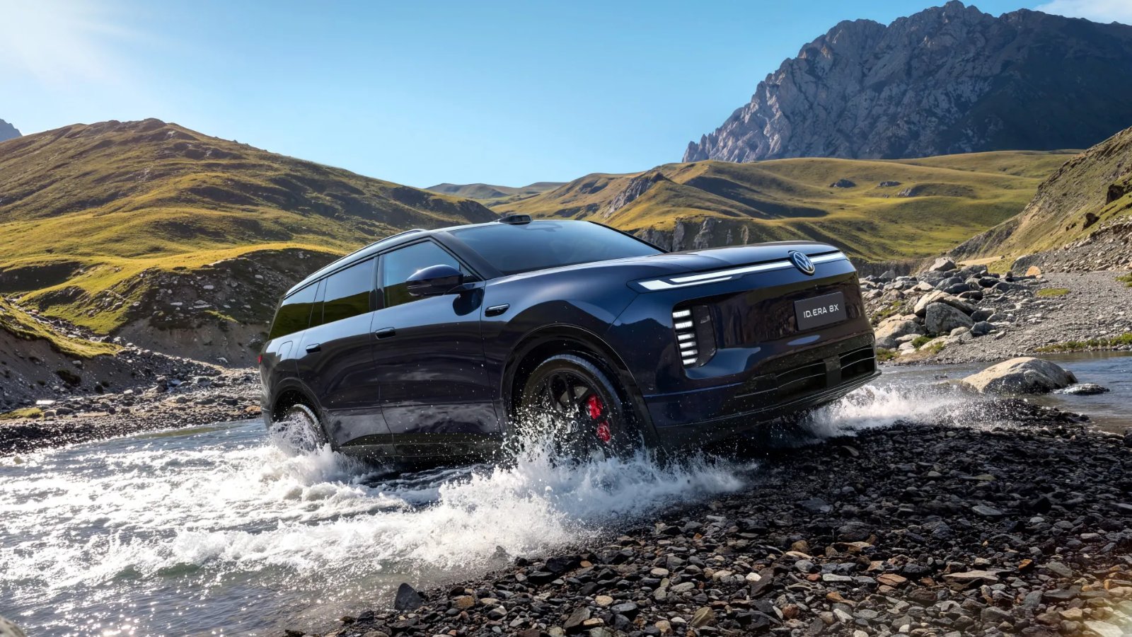A blue Volkswagen ID. ERA 8X SUV drives through a shallow stream in a mountainous landscape.