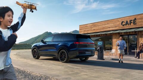 Rear three-quarter view of a blue Volkswagen ID. ERA 8X beside a charging station outside a cafe.