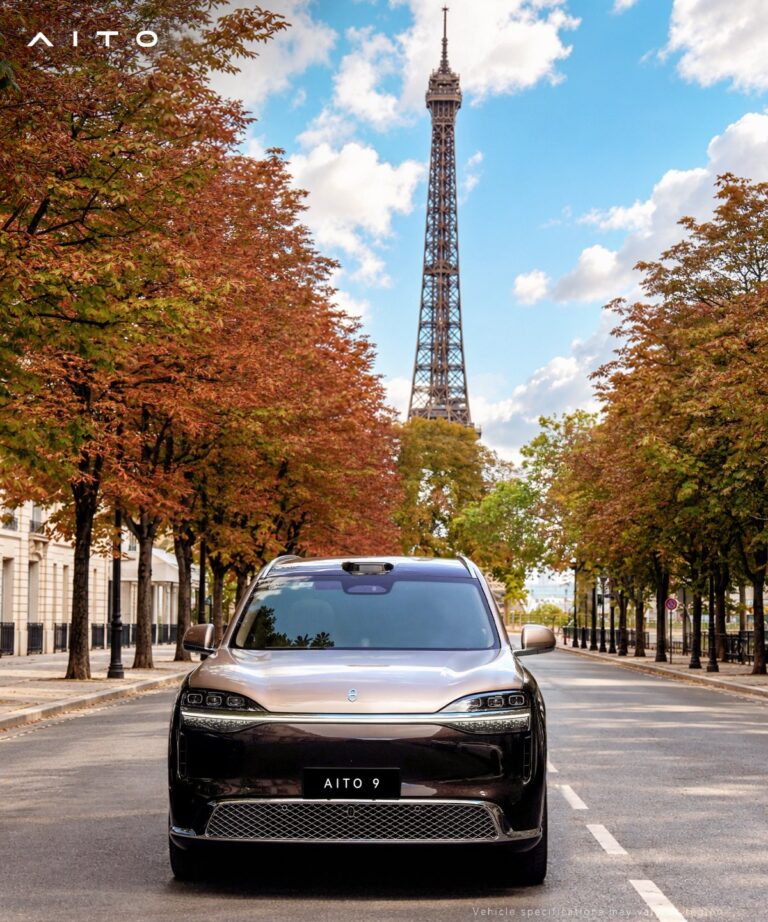 Front view of an Aito 9 SUV on a tree-lined street with the Eiffel Tower in the background.