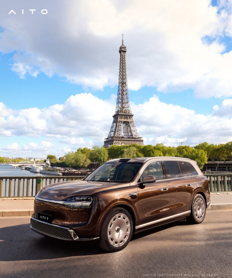 Brown Aito 9 SUV beside a riverside railing with the Eiffel Tower in the background.