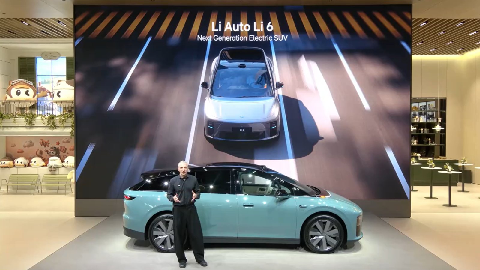 Benjamin Baum speaks beside a light blue Li 6 SUV at the 2026 Paris auto show.