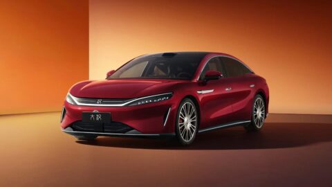 Red BYD Da Han EV shown from the front against an orange backdrop.