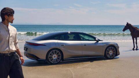 Silver BYD Da Han EV parked on a beach, with a man and a horse nearby.