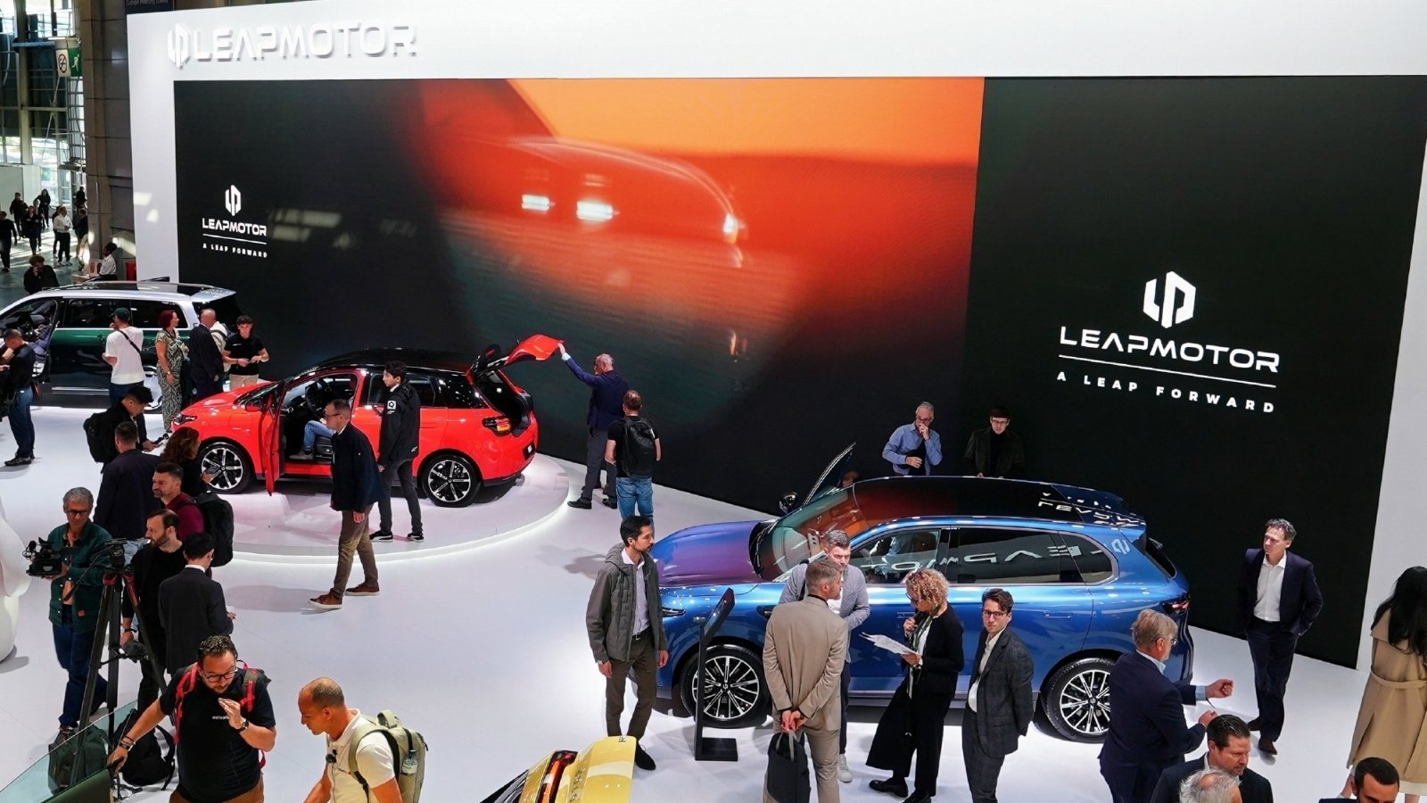 Visitors view a red hatchback and a blue SUV at Leapmotor's Paris Motor Show booth.