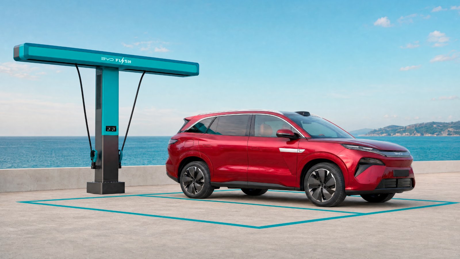 Red BYD Atto 8 parked beside a flash charging station overlooking the sea.