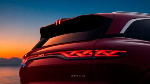 Close-up of the BYD Atto 8's illuminated rear light bar, roof spoiler and model badge at sunset.