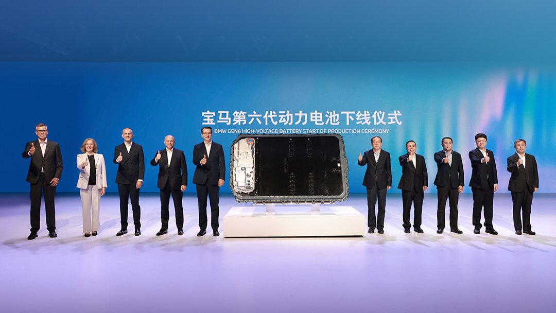 Attendees pose beside a battery pack at BMW's Gen 6 battery production launch ceremony.