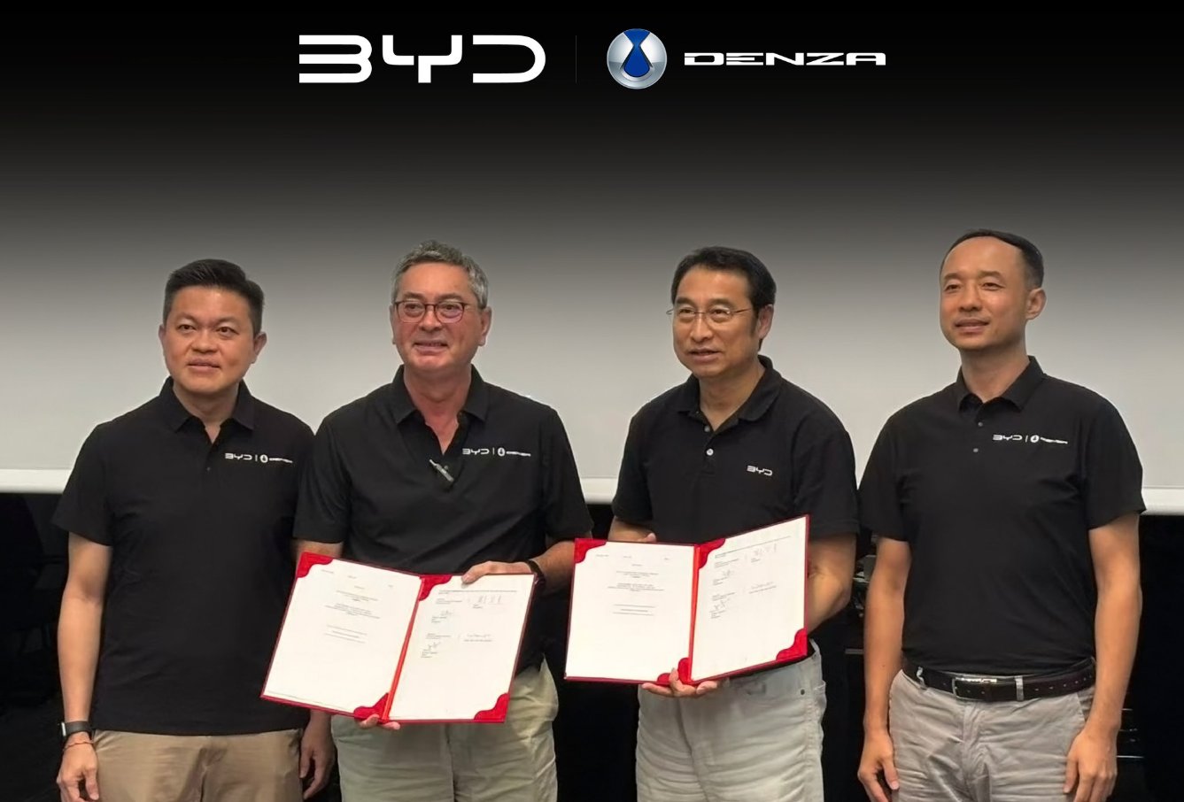 4 men pose beneath BYD and Denza logos, with the 2 in the center holding open document folders.