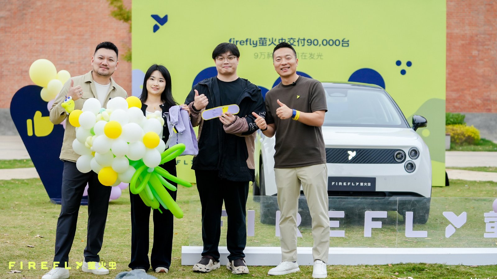 4 people pose with a balloon bouquet in front of a white Firefly EV at the brand's 90,000th vehicle delivery ceremony.