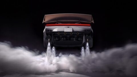 Rear view of the Tesla Roadster suspended above the ground, with downward jets and clouds beneath it.