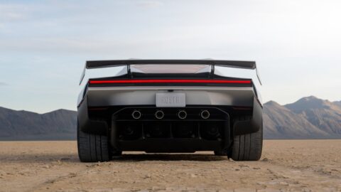 Rear view of the Tesla Roadster with its wing raised in a desert landscape.