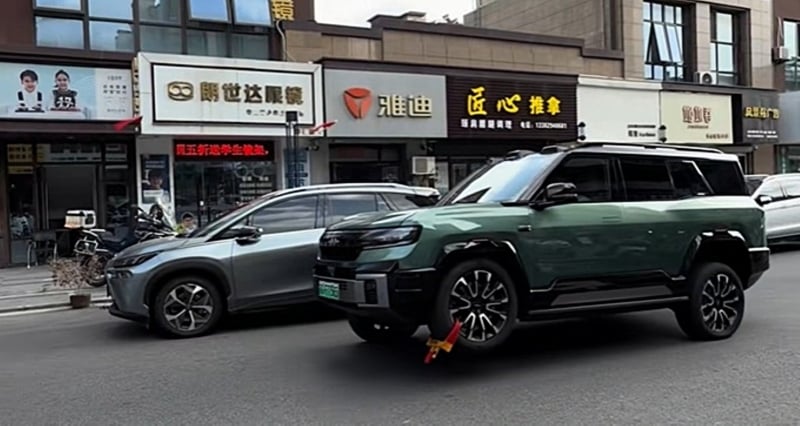 BYD Fang Cheng Bao Bao 8 with a yellow-and-red metal wheel clamp attached to its raised front-left wheel