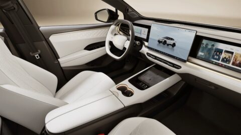 Volkswagen ID. UNYX 06 interior with light-colored front seats, multiple dashboard screens and a center console with cupholders.