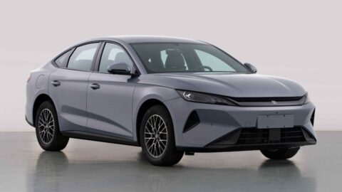 Front three-quarter view of a gray BYD Qin Plus EV with slim headlights and multi-spoke wheels.