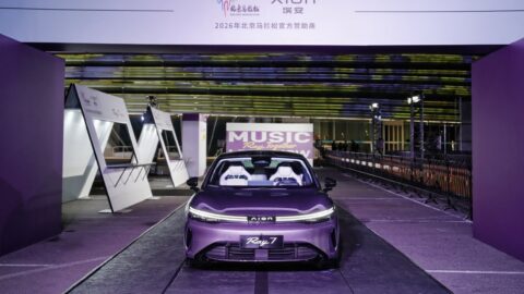 Front view of a purple GAC Aion Ray 7 at an indoor display with purple lighting.
