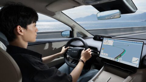 Driver at the wheel of a GAC Aion Ray 7, with a navigation map on the central touchscreen.
